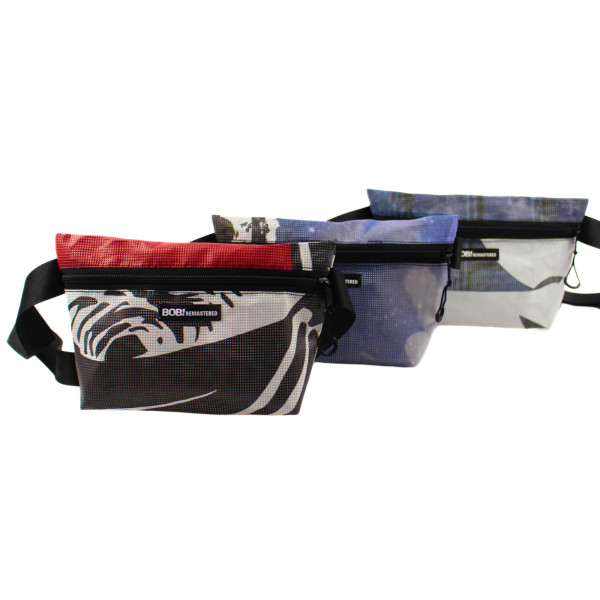 Drei Bauchtaschen mit Reißverschluss und verstellbarem Gurt in verschiedenen Farben und Mustern. Jede Tasche trägt ein schwarzes Label mit der Aufschrift „BOB! REMASTERED“. Die Farben reichen von Rot-Schwarz über Blau bis zu Blau-Weiß.