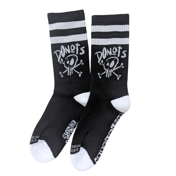 Schwarze Socken mit weißen Zehen- und Fersenpartien sowie zwei weißen Streifen am oberen Rand. Auf dem Schaft ist ein weißes Totenkopf-Motiv mit gekreuzten Knochen und der Aufschrift „DONOTS“ abgebildet.